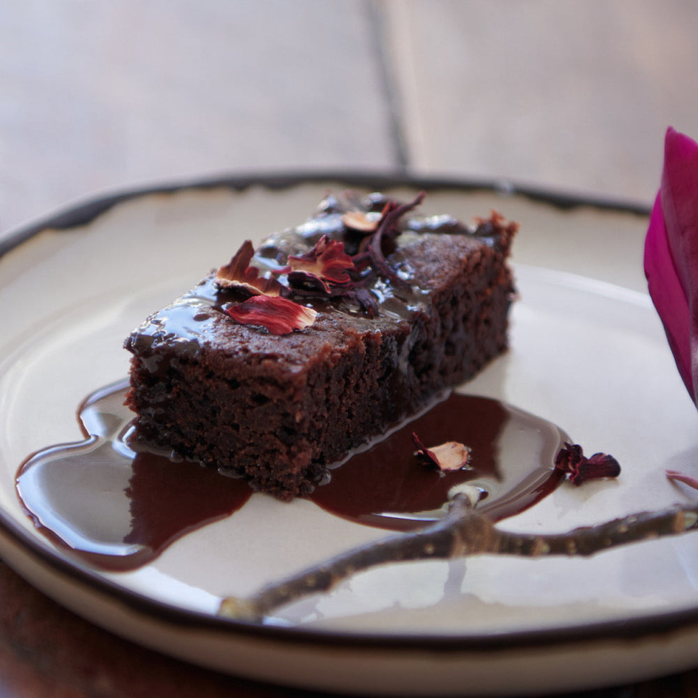 A piece of chocolate pudding topped with chocolate sauce on a plate.